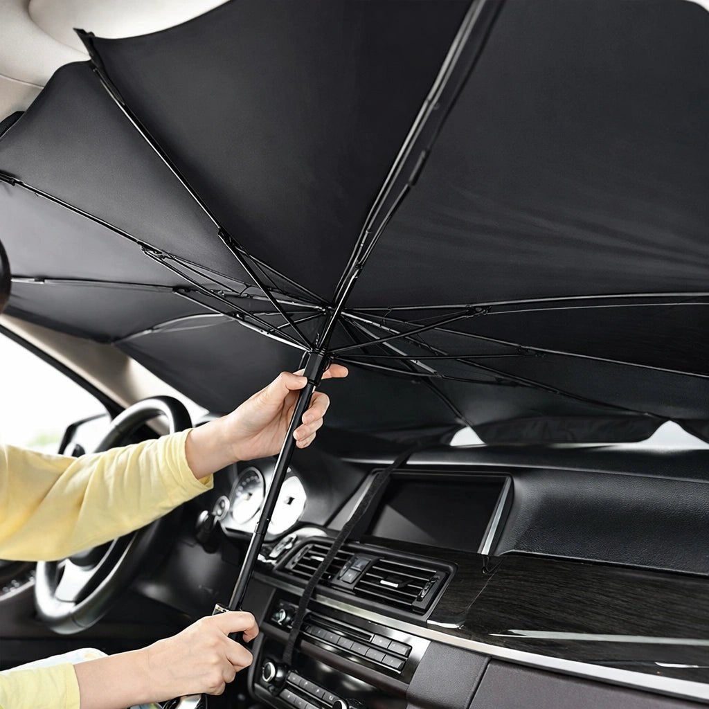 Hands unfolding black umbrella-style sunshade inside car to shield dashboard and interior from sunlight and heat.