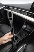 Hand holding black car seat gap filler organizer designed to prevent items from falling between seat and console