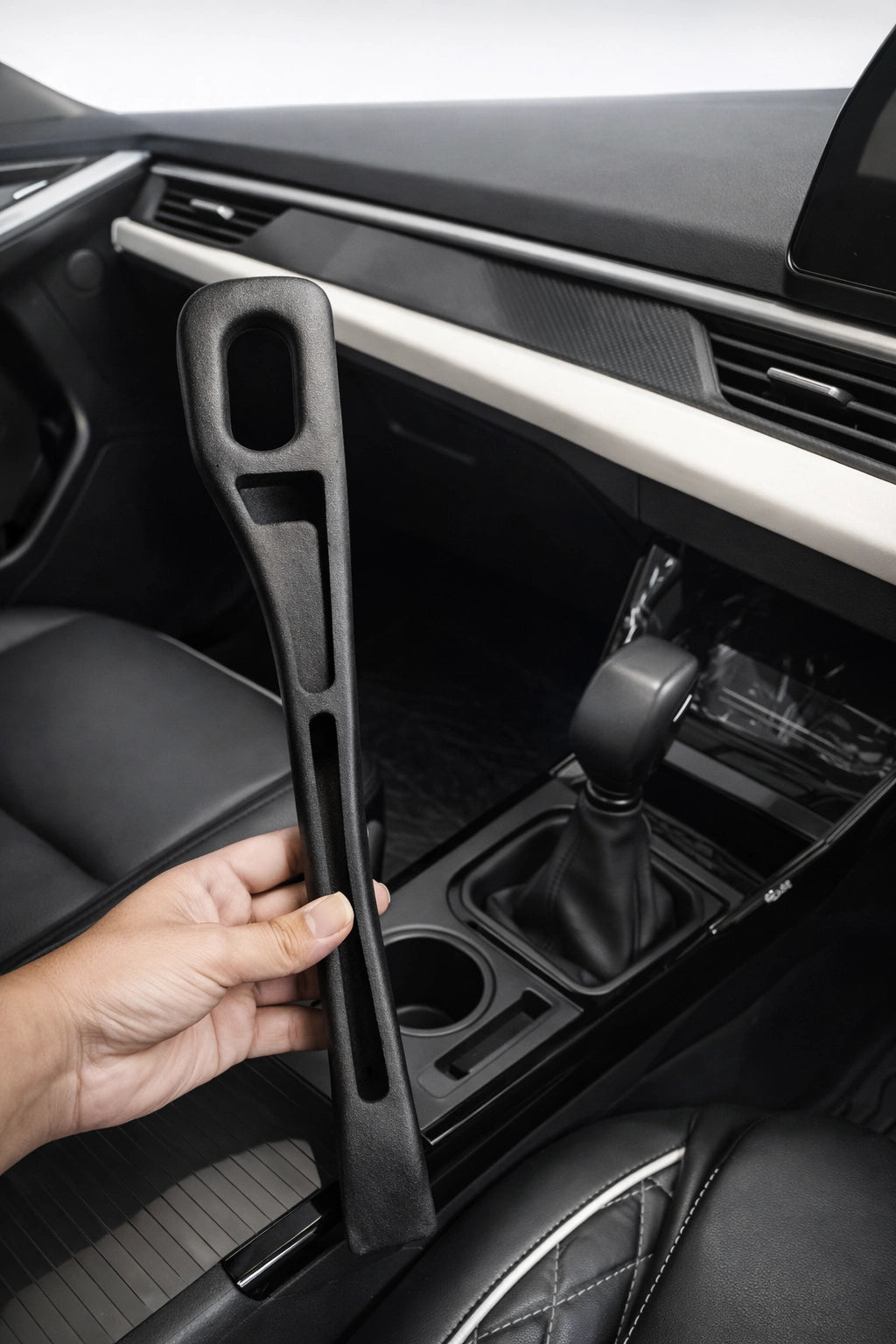 Hand holding black car seat gap filler organizer designed to prevent items from falling between seat and console