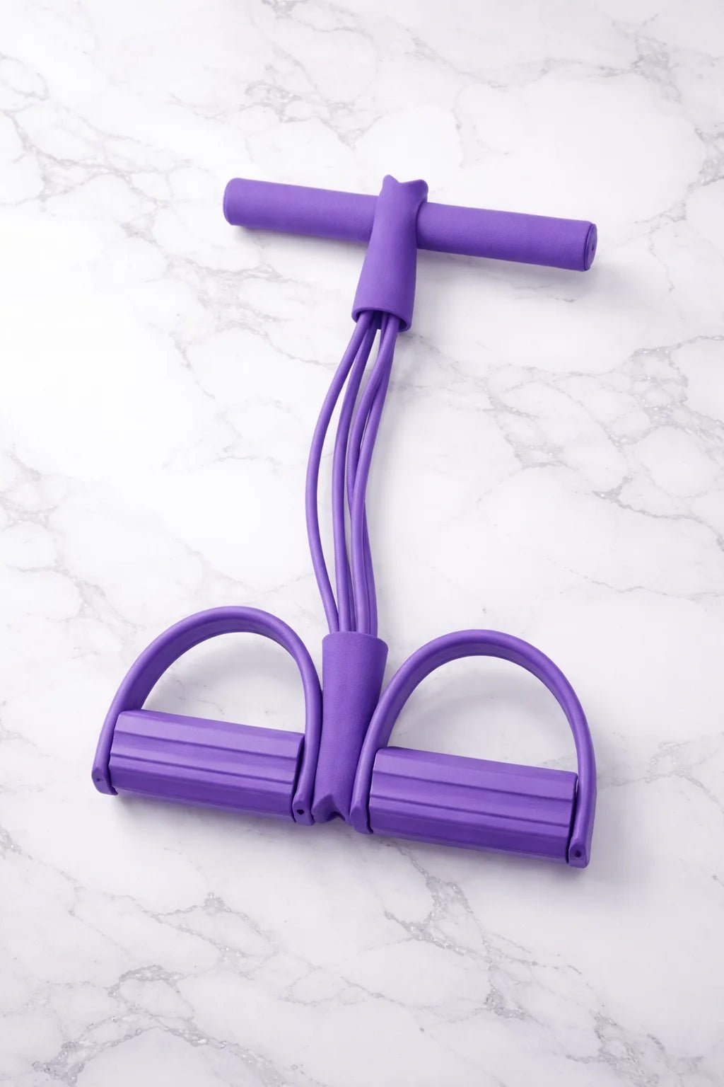 Purple resistance band with foam handle grips and foot pedals for versatile full-body exercise workouts at home or gym